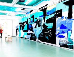 Contemporary art gallery installation in W139, featuring a 30 meter long mural/ceiling painting by Axel Linderholm. Geometrical shapes in different shades of vibrant blues, black and white, suggest a cascading movement.