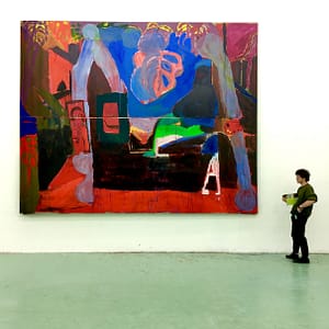 Man standing beside a large abstract painting of Axel Linderholm during Studio Double V exhibition. The painting features vibrant red, blue, and green shapes, with bold, expressive brushstrokes and organic forms on a large canvas.